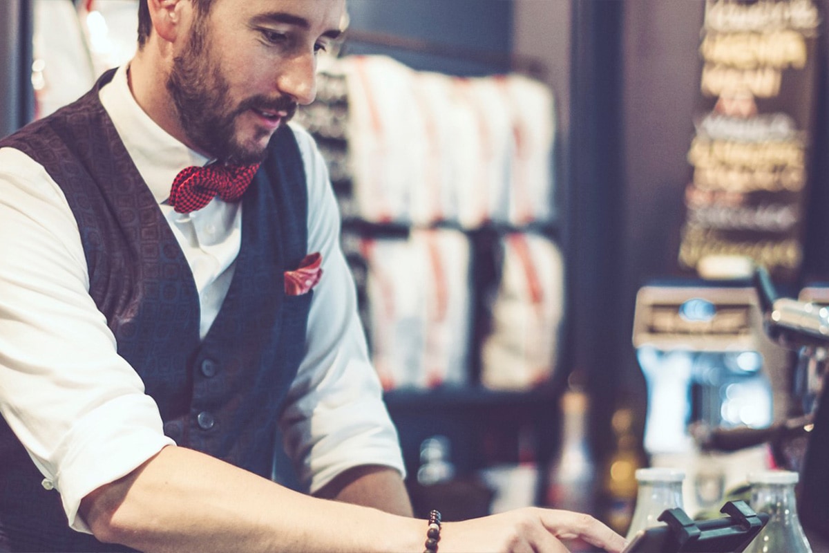 custom-configurations Cashier with bowtie inputting something on POS system