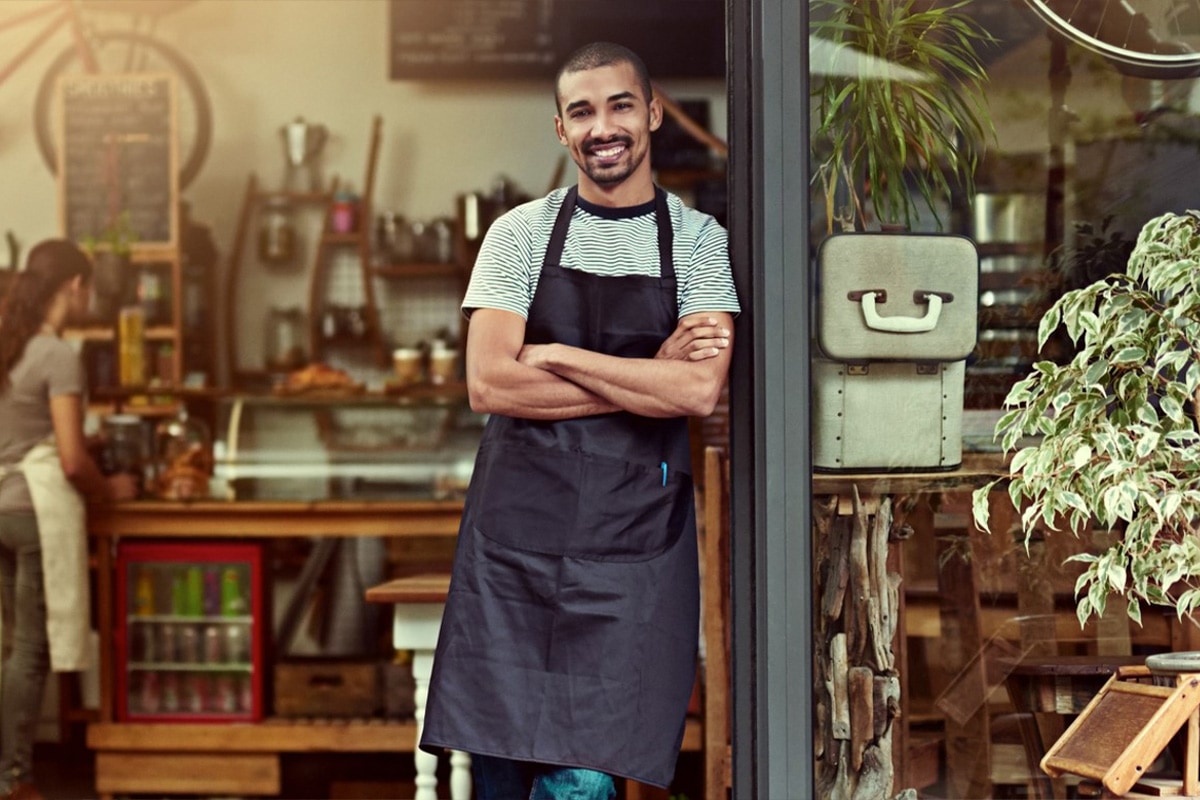 customized-recommendations Cafe owner smiling with arms crossed standing in the entrance of his store