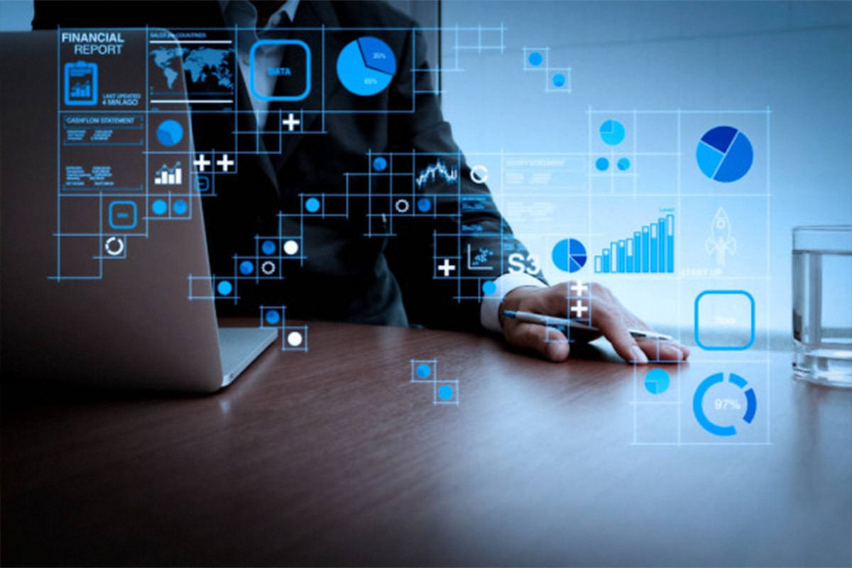 dashboard-analytics Hand holding a pen next to a laptop with overlaid with data and analytics infographics