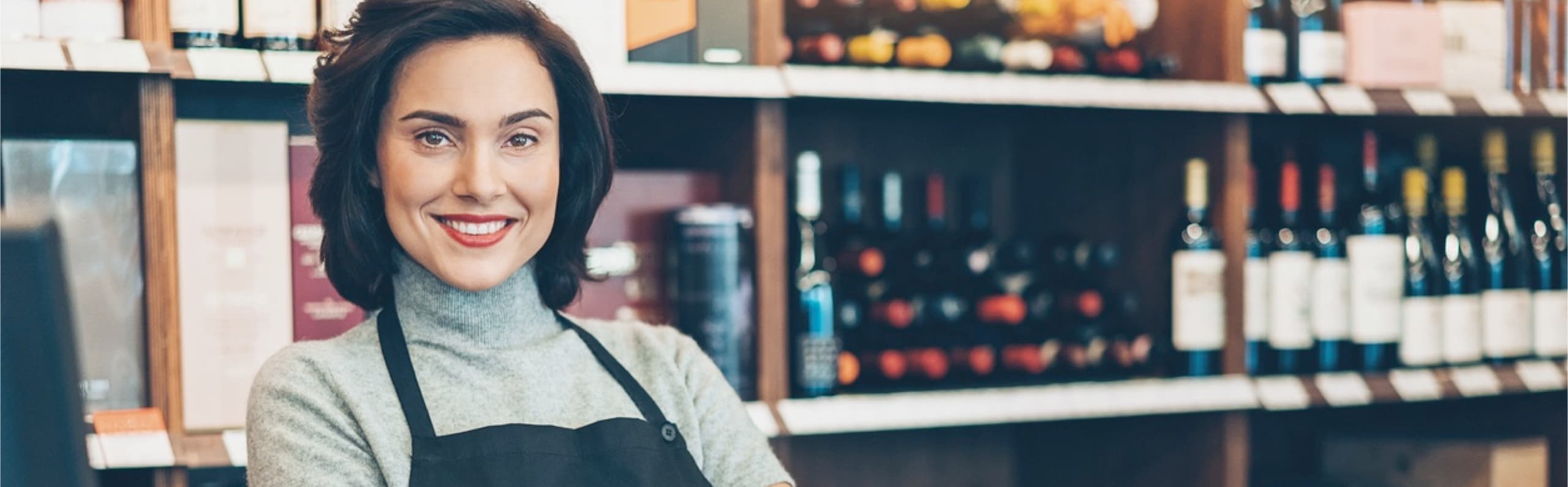 Liquor store clerk smiling in front of wine display